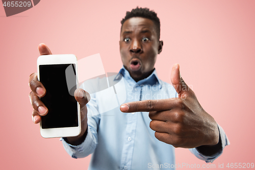 Image of Indoor portrait of attractive young black man holding blank smartphone