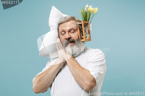 Image of Tired man sleeping at home having too much work. Bored businessman with pillow and hourglass