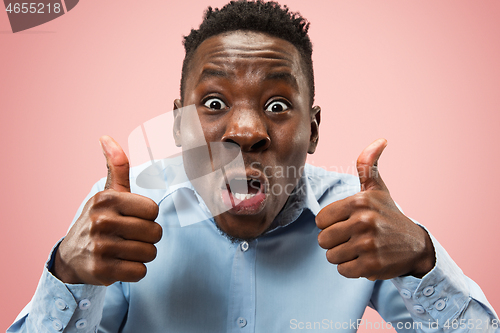 Image of The young attractive man looking suprised isolated on pink