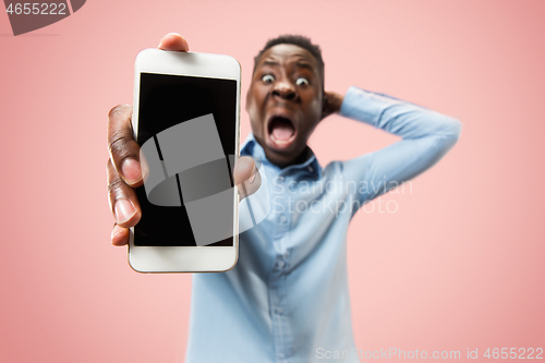 Image of Indoor portrait of attractive young black man holding blank smartphone