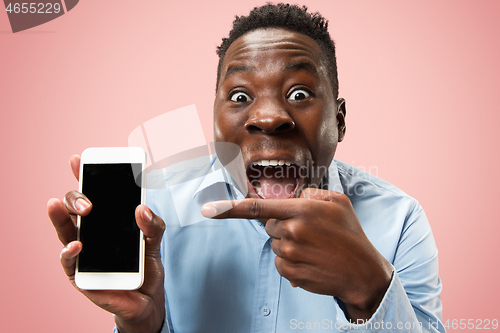 Image of Indoor portrait of attractive young black man holding blank smartphone