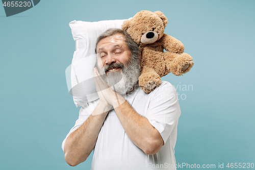 Image of Tired man sleeping at home having too much work. Bored businessman with pillow and toy bear