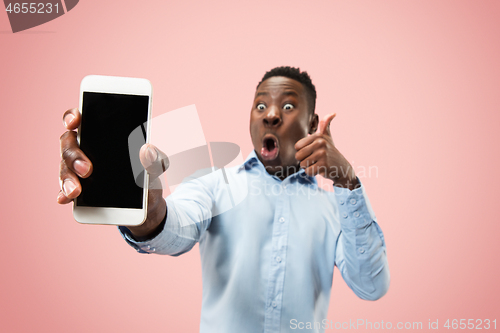 Image of Indoor portrait of attractive young black man holding blank smartphone