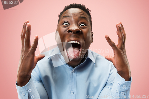 Image of The young attractive man looking suprised isolated on pink