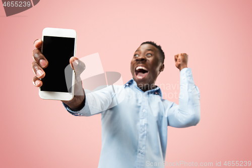 Image of Indoor portrait of attractive young black man holding blank smartphone