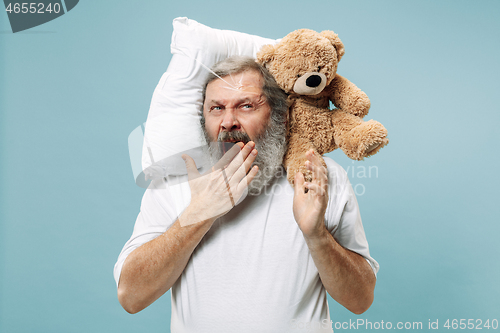 Image of Tired man sleeping at home having too much work. Bored businessman with pillow and toy bear