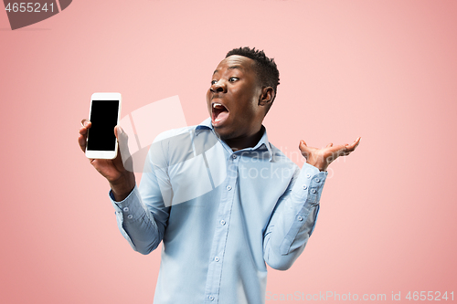 Image of Indoor portrait of attractive young black man holding blank smartphone