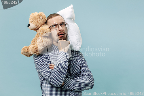 Image of Tired man sleeping at home having too much work. Bored businessman with pillow and toy bear