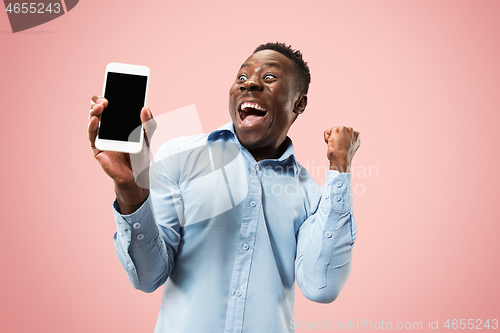 Image of Indoor portrait of attractive young black man holding blank smartphone