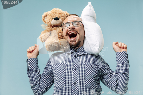 Image of Tired man sleeping at home having too much work. Bored businessman with pillow and toy bear