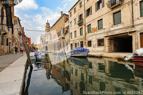 Image of Venice, Italy. Tourists walking at sidewalks aside to canals in historic part of the city