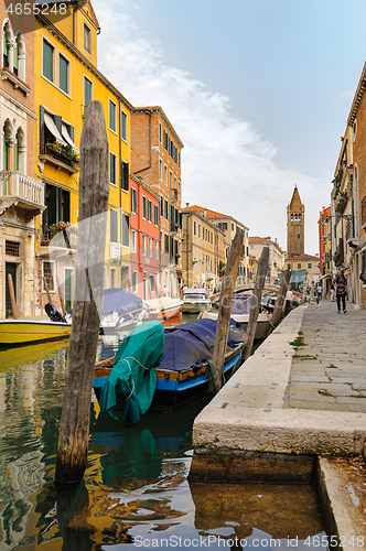 Image of Venice, Italy. Tourists walking at sidewalks aside to canals in historic part of the city