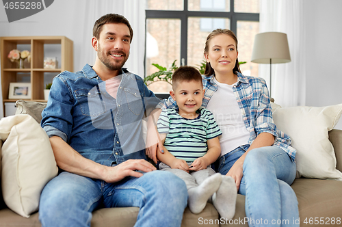 Image of portrait of happy family sitting on sofa at home