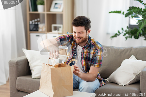 Image of smiling man unpacking takeaway food at home