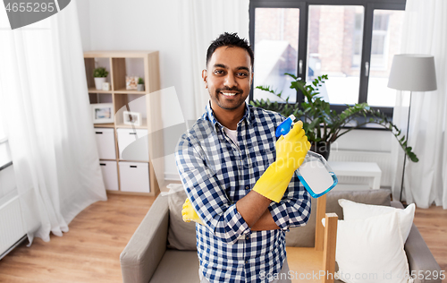 Image of smiling indian man with detergent cleaning at home