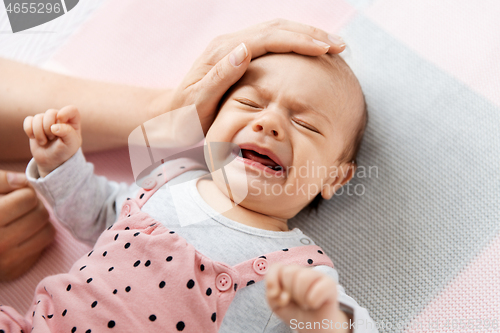 Image of mother\'s hand touching crying little baby daughter