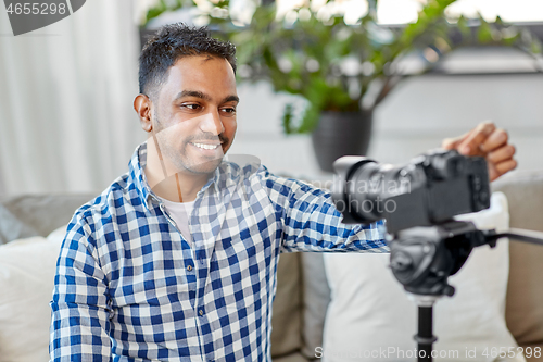 Image of indian male video blogger adjusting camera at home