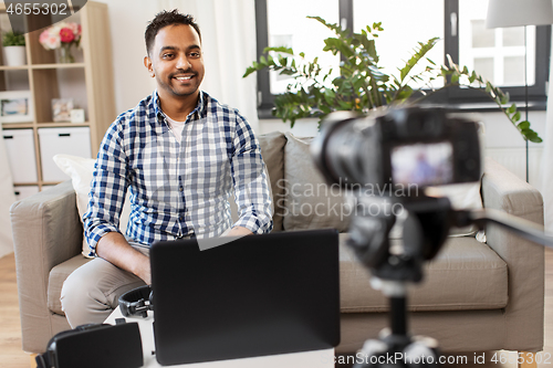 Image of male blogger with camera videoblogging at home