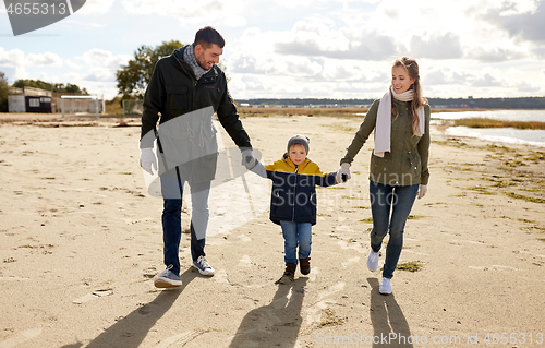 Image of happy family walking along autumn beach