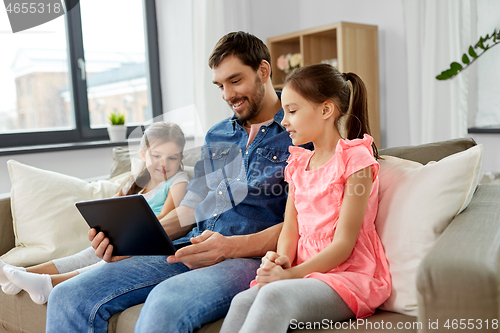 Image of happy father and daughters with tablet pc at home