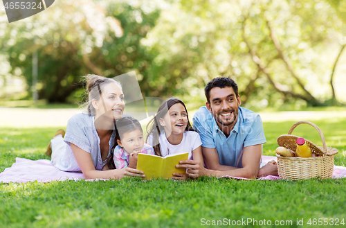 Image of family reading book on picnic in summer park