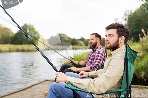 Image of male friends with fishing rods on lake