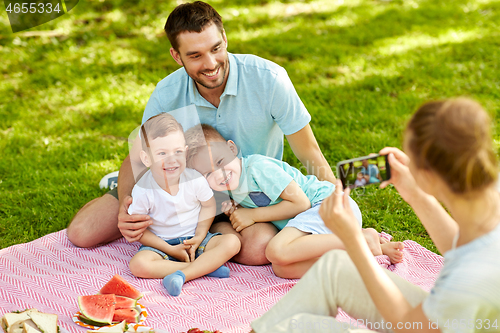 Image of mother taking picture of family on picnic at park