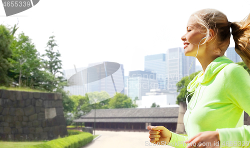 Image of woman with earphones running at city park