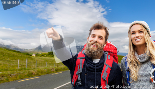 Image of smiling couple with backpacks hiking in autumn