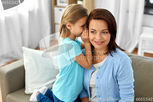 Image of daughter whispering secret to mother at home