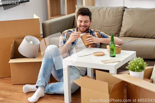 Image of smiling man eating takeaway food at new home