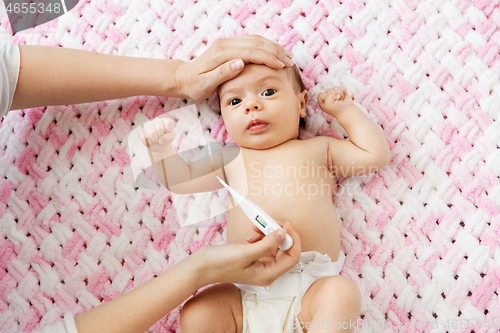 Image of mother\'s hands measuring temperature of baby girl