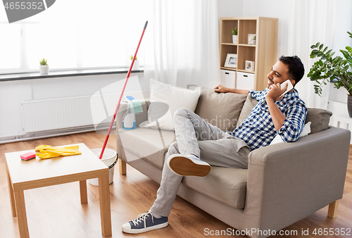 Image of man calling on smartphone after cleaning home