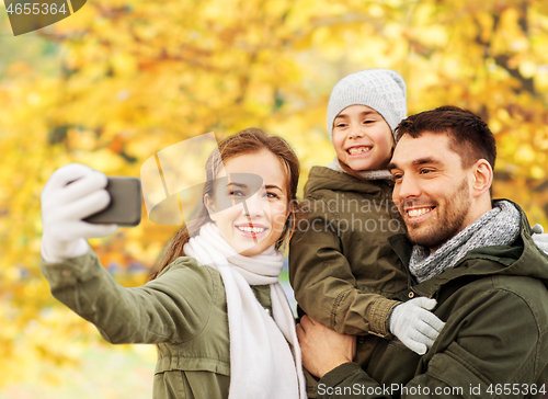 Image of family taking selfie by smartphone in autumn park