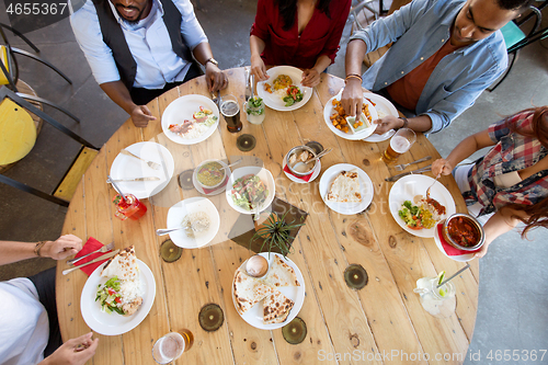 Image of international friends eating at restaurant