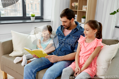 Image of happy father with daughters reading book at home