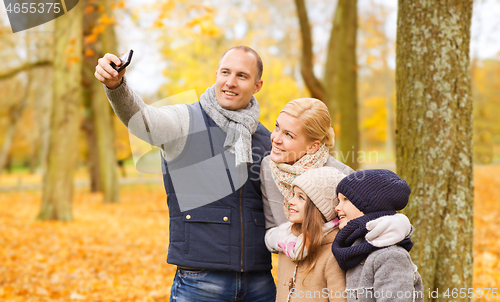 Image of happy family with camera in autumn park