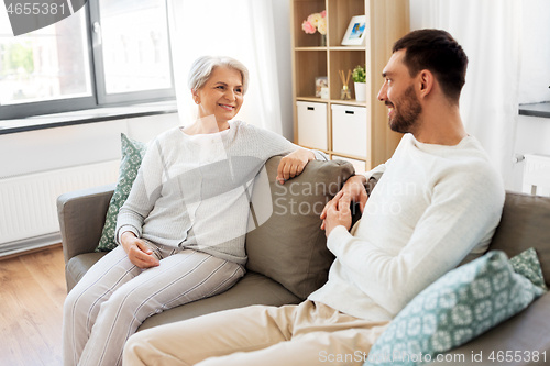 Image of senior mother talking to adult son at home