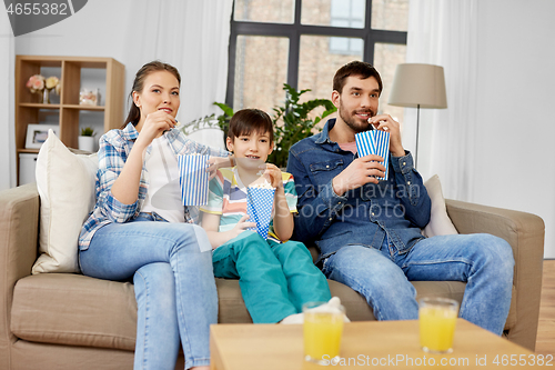 Image of happy family with popcorn watching tv at home