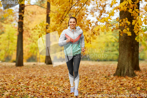 Image of young woman running in autumn park