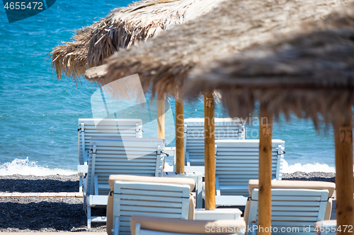 Image of beach with umbrellas and deck chairs by the sea in Santorini