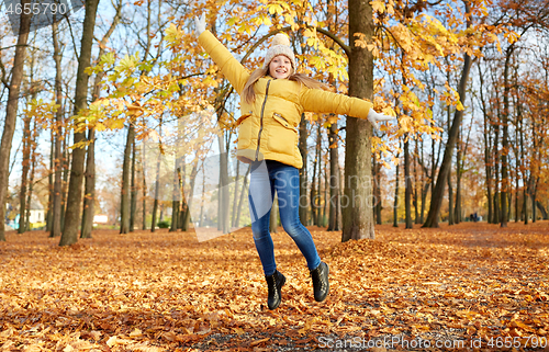 Image of happy girl jumping at autumn park