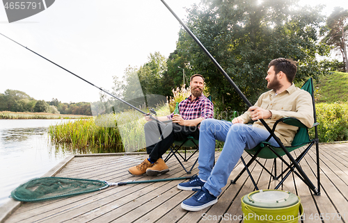 Image of male friends fishing and drinking beer on lake