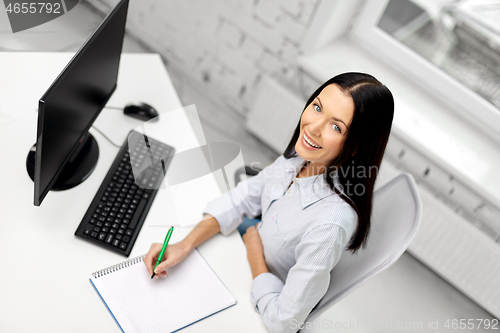 Image of businesswoman writing to notebook at office