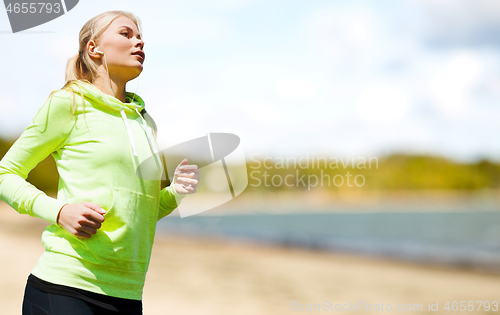 Image of woman with earphones running at park