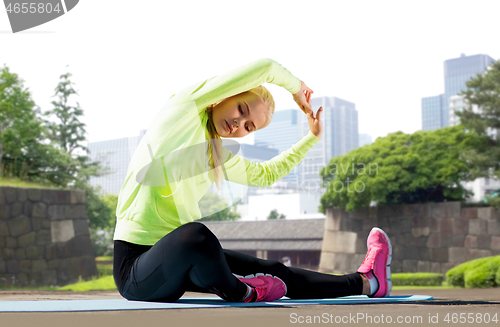 Image of woman stretching on exercise mat at city park