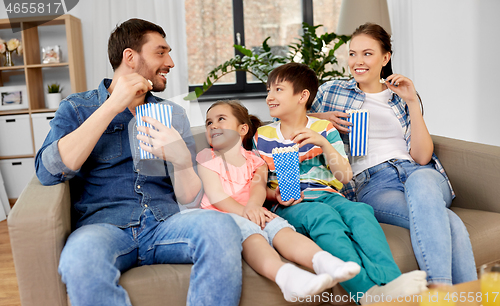 Image of happy family with popcorn watching tv at home