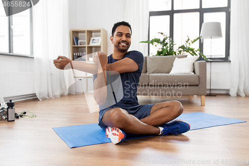 Image of man training and stretching arm at home