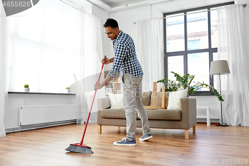 Image of man with broom cleaning floor at home