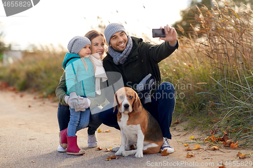 Image of happy family with dog taking selfie in autumn